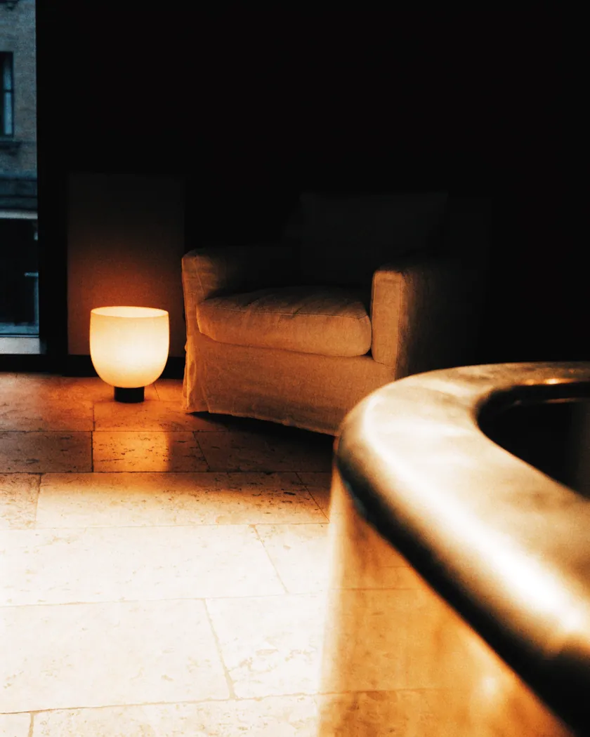 Hotellobby in der Dämmerung, warmes Lampenlicht auf Stein und Messing