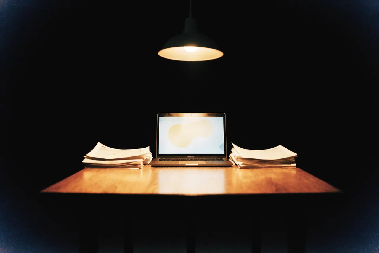 Aufgeklappter Laptop mit unscharfem Diagramm und gedruckte Reports auf demselben Tisch